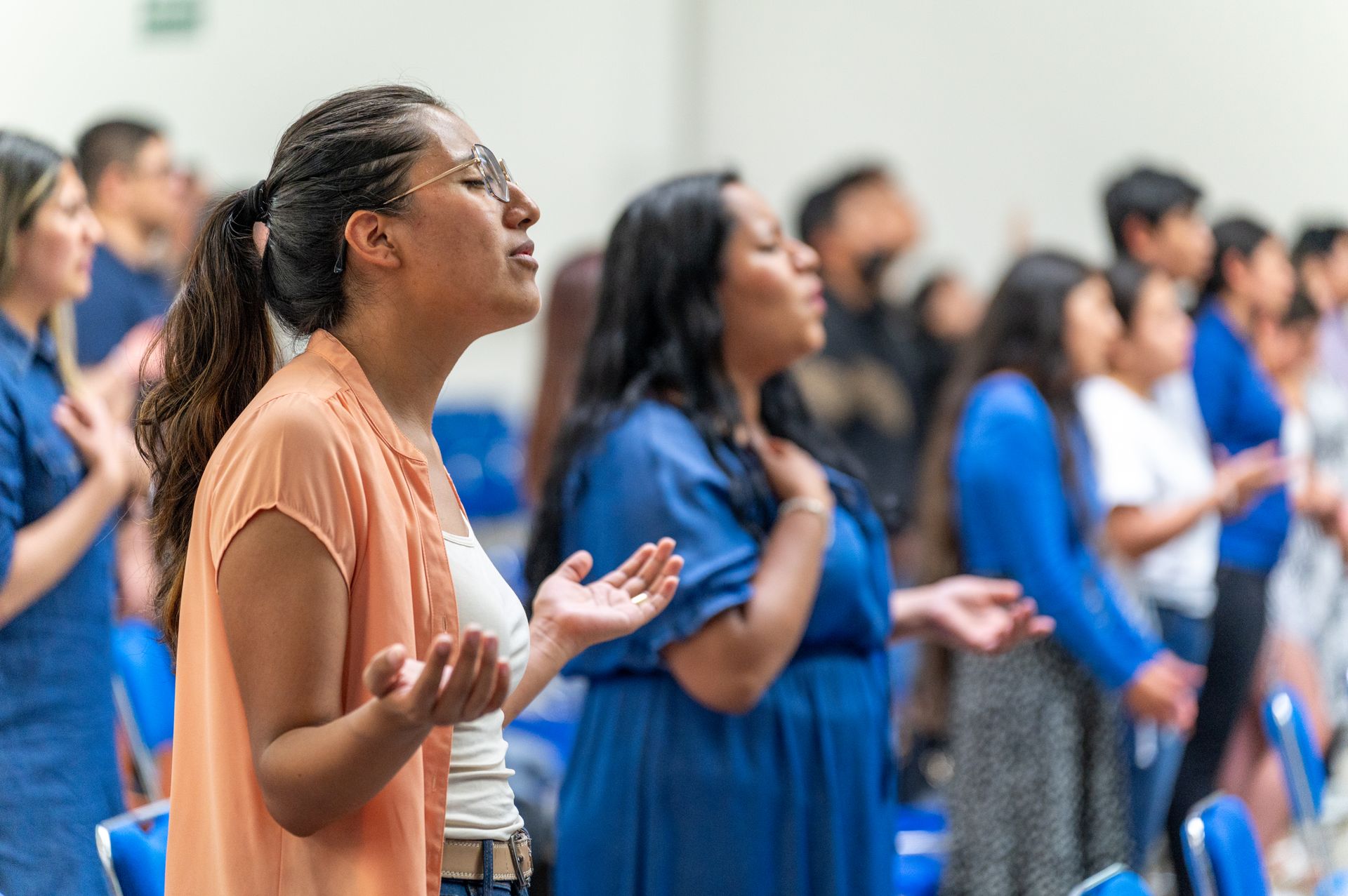 Personas adultas reunidas en oración durante un servicio cristiano.